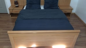 A bed with a wooden frame, two bedside tables, and a lamp on one table. - HOMEWAY LILLE (Lille)