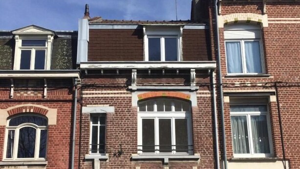 A row of terraced houses with multiple windows and a garage door. - HOMEWAY LILLE (Lille)