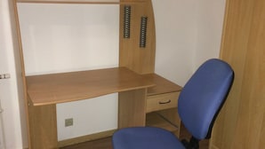 A small room with a wooden desk, a blue office chair, and a wooden wardrobe. - HOMEWAY LILLE (Lille)