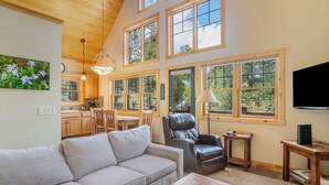 A spacious living room with a sofa, a leather chair, a wooden coffee table, and a TV mounted on the wall. - Solitude Bobcat #5- Estes Park 2 Bedroom Condo by RedAwning (Estes Park)