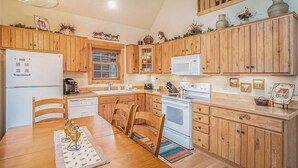 A kitchen with wooden cabinets, a white refrigerator, a microwave, and a stove.
