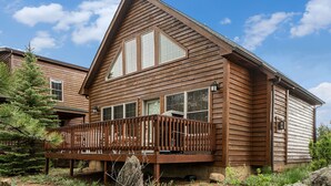 A wooden cabin with a balcony, large windows, and a clear sky.