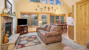 A spacious living room with a fireplace, a television, a large window, and a dining area.