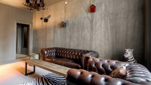 A modern living room with a leather sofa, a wooden bench, and decorative animal figures. - hotel montagne (Åmmeberg)