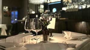 A restaurant table set with wine glasses, a vase with flowers, and cutlery. - hotel montagne (Åmmeberg)
