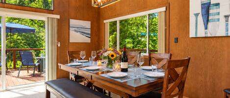 A dining area with a wooden table set for four, a bench, and a view of the outdoors.