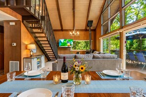A modern interior with a dining area, a sofa, and a TV in the background.