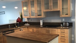 A modern kitchen with wooden cabinetry, a central island, and a built-in oven.