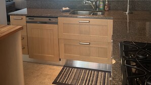 A modern kitchen with granite countertops, wooden cabinets, a built-in dishwasher, and a gas stove.