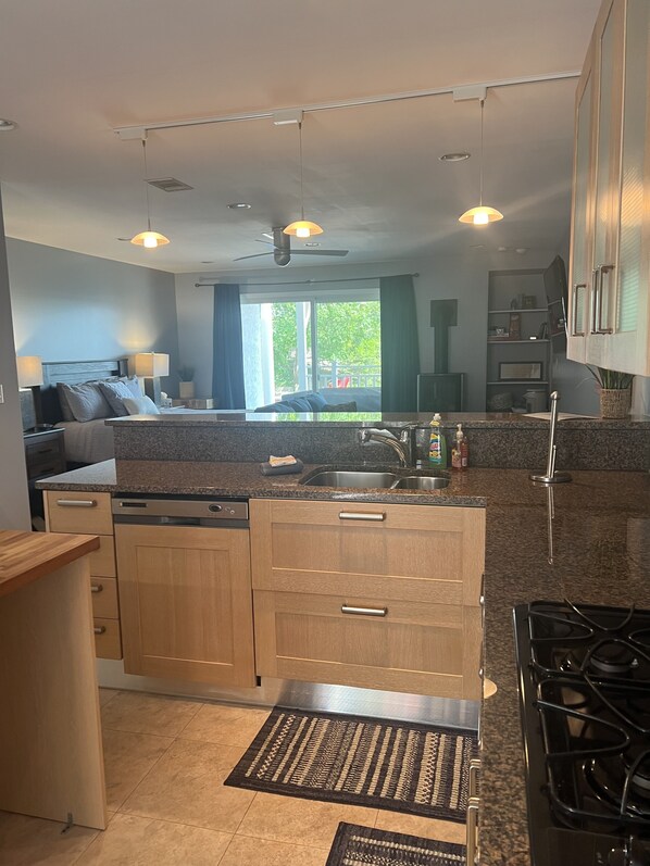 A modern kitchen with granite countertops, wooden cabinets, a built-in dishwasher, and a gas stove.
