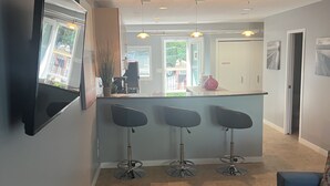 A modern kitchen with a bar area, a dining area with a blue sofa, and a living room with a coffee table.