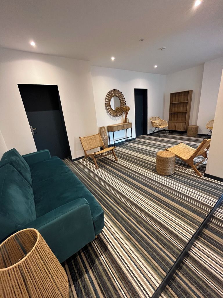 Una sala de estar moderna con alfombra a rayas, un sofá color turquesa y una mesa de centro redonda.