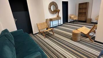 Una sala de estar moderna con alfombra a rayas, un sofá color turquesa y una mesa de centro redonda.