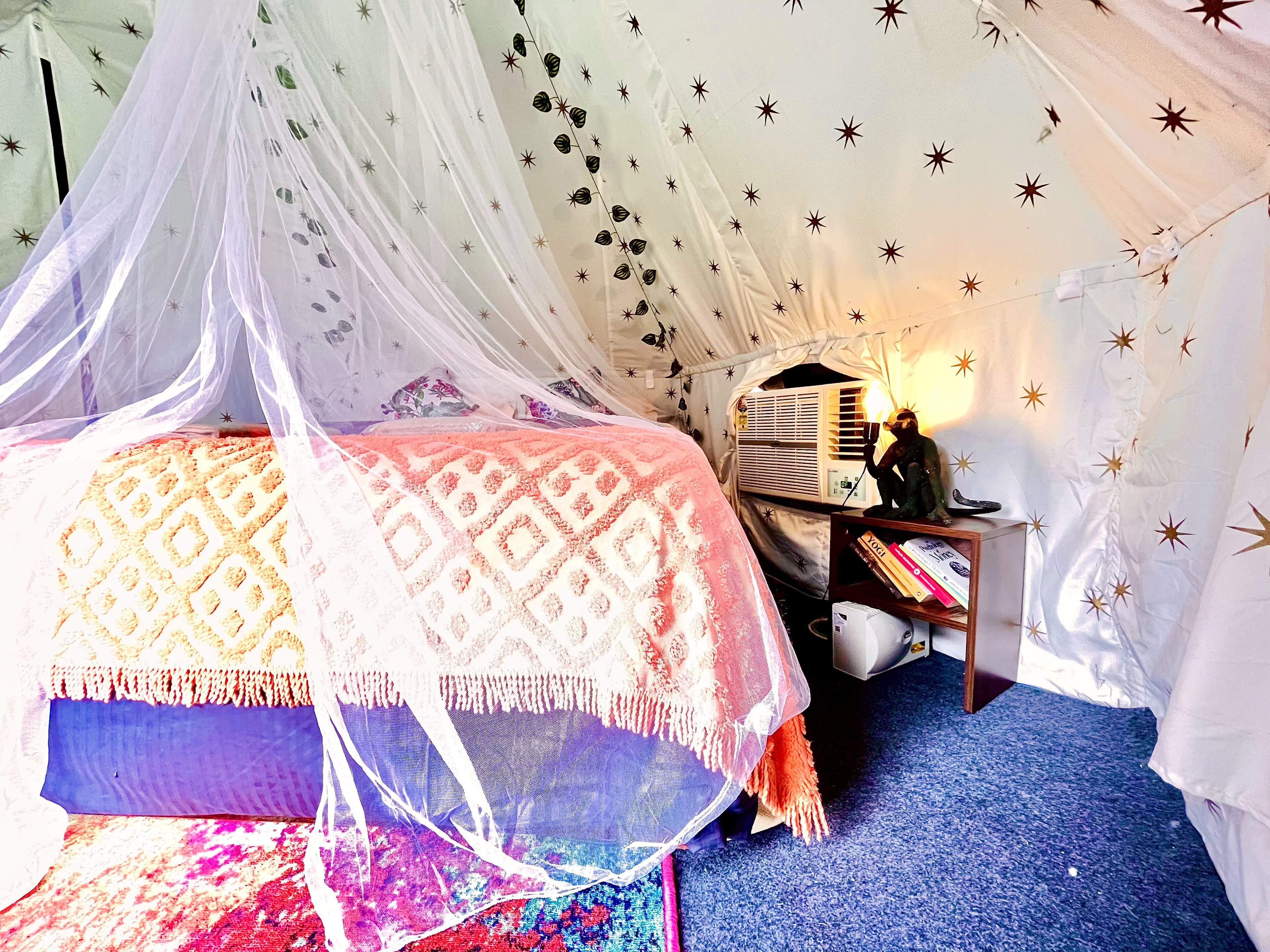 Un dormitorio con una cama, una mesita de noche, una lámpara y un aire acondicionado instalado en la pared.