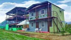 A two-story building with a balcony, a covered outdoor area, and a small garden. - Antrix Resorts & Retreat (Yamkeshwar)