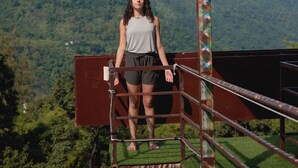 A person standing on a balcony with a view of a mountain and forest. - Antrix Resorts & Retreat (Yamkeshwar)