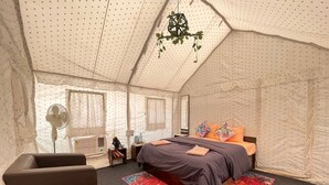 A tent-style bedroom with a bed, a chair, and a hanging plant. - Antrix Resorts & Retreat (Yamkeshwar)