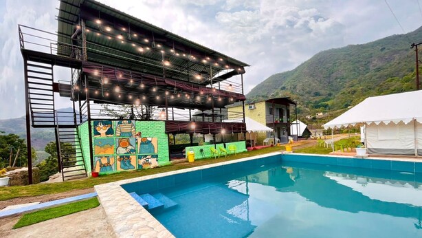 A pool area with a multi-level structure, outdoor seating, and a mural on the side. - Antrix Resorts & Retreat (Yamkeshwar)