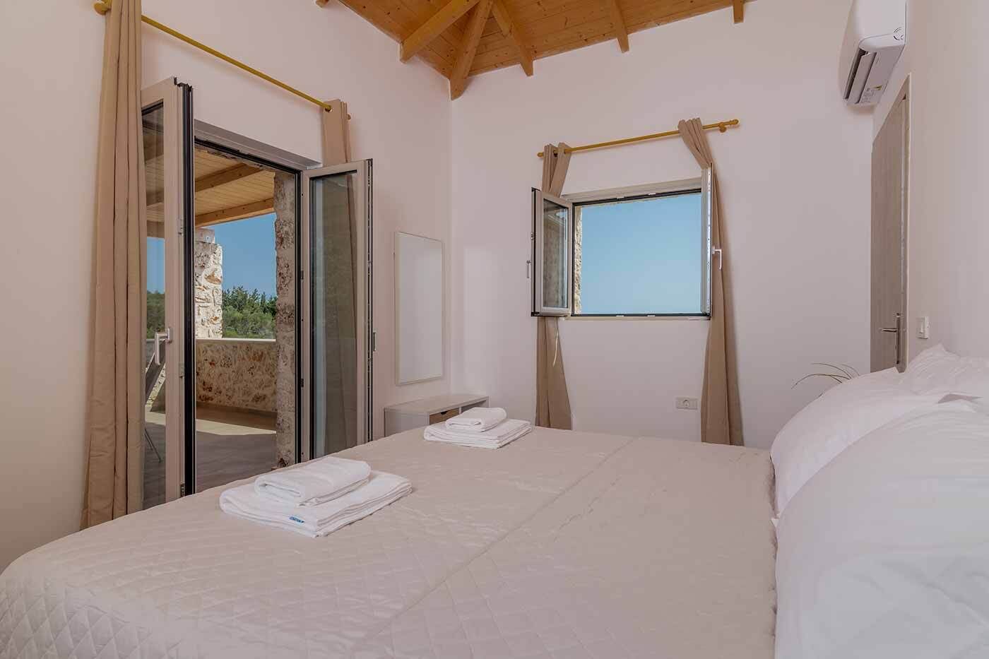 A bedroom with a bed, a window, and a door leading to an outdoor area.