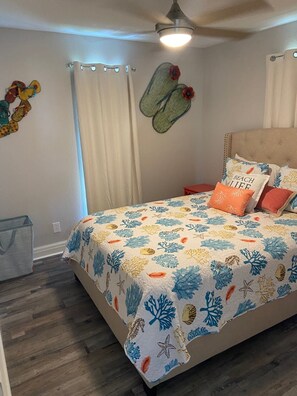 A bedroom with a bed, a ceiling fan, and a wall decoration.