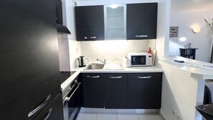 A compact kitchen with black cabinets, a microwave, a kettle, and a sink. - Sunlight Properties MIRAGE - Nice centre with parking & terrace (Nice)
