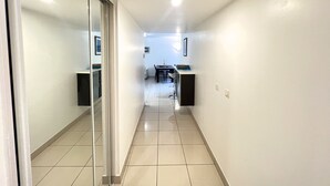 A hallway with a glass door on the left, a dining area with a table and chairs in the center, and a kitchen area with cabinets and a countertop on the right. - Sunlight Properties MIRAGE - Nice centre with parking & terrace (Nice)