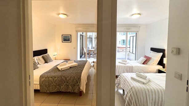 A hotel room with two beds, a dining area, and a view of the outside. - Sunlight Properties MIRAGE - Nice centre with parking & terrace (Nice)