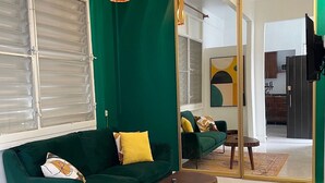 Un saló amb un sofà verd, una taula de centre i una catifa colorida.
