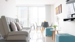 A modern living room with a sofa, a dining table with chairs, and a small side table.