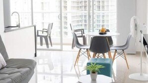 A modern living room with a grey sofa, a small round table with a plant, and a white fan.