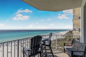 Un balcon avec vue sur la plage et l’océan, comprenant deux chaises et une table.