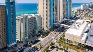 A high-rise hotel with multiple floors, a parking area, and a view of the ocean.