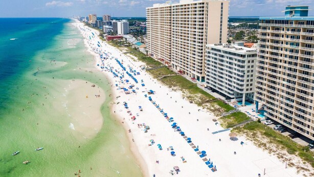 A beach resort with a long stretch of beach, multiple hotel buildings, and clear blue waters.