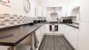A modern kitchen with white cabinets, a black countertop, and a patterned backsplash. - Kingfisher Lodge (Great Yarmouth)
