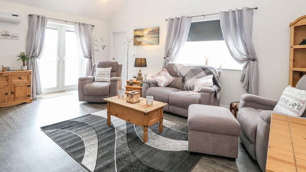 A modern living room with a sofa set, a wooden coffee table, and a grey rug. - Kingfisher Lodge (Great Yarmouth)