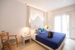A bedroom with a bed, a nightstand, a chair, and a window with curtains.