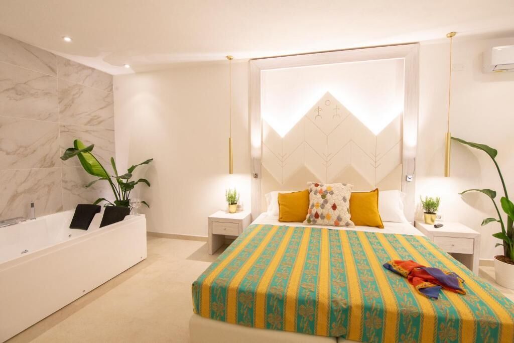 Un dormitorio moderno con una cama grande, una bañera integrada y dos mesitas de noche con lámparas.