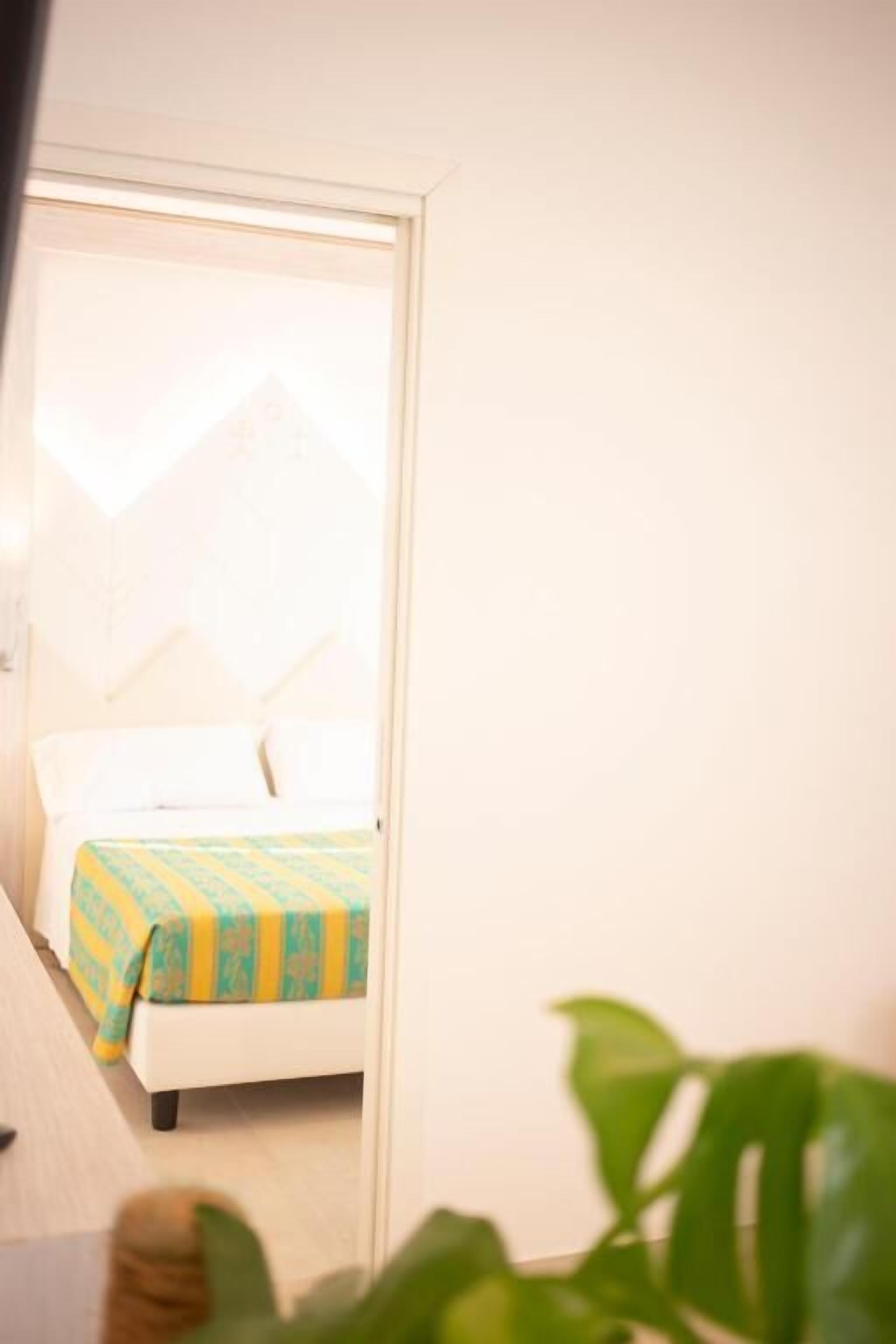 A small, brightly lit room with a bed and a window.