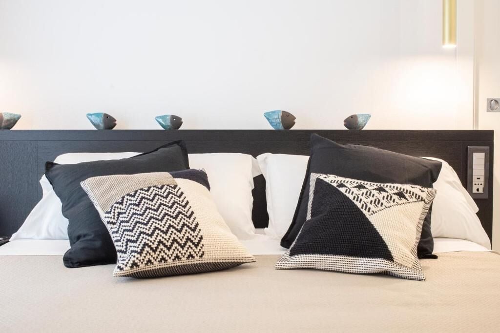 Un lit avec des oreillers à motifs et des objets décoratifs en forme de poisson sur la tête de lit.