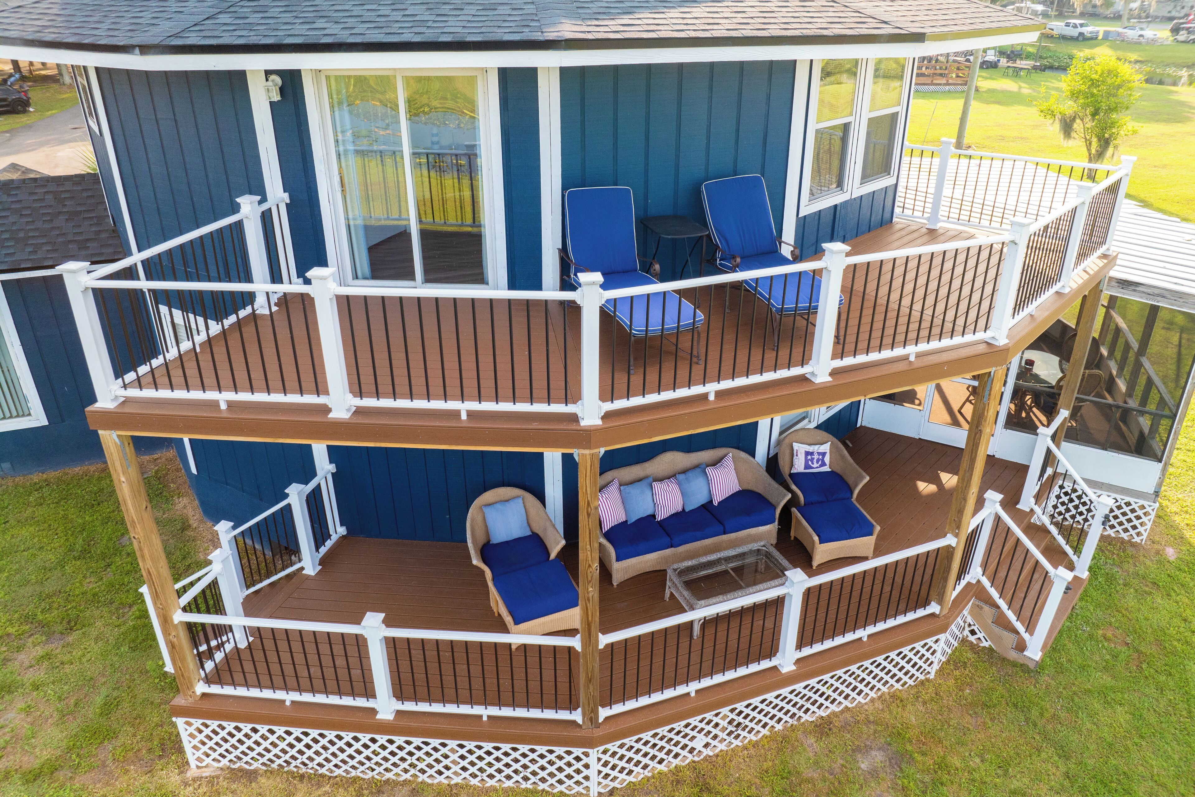 A two-story deck with blue outdoor furniture, a glass door, and a white railing.