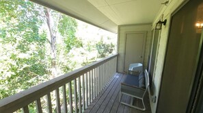 Enjoy a peaceful view of lush greenery from this room's balcony, which features a table and chair.