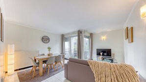 A modern living room with a sofa, a dining table, and a TV.