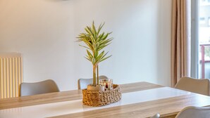 A dining table with a woven basket containing a potted plant and a candle.