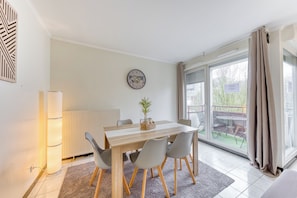 Ein stilvoller Essbereich mit einem Holztisch und Stühlen, einer Wanduhr und Blick ins Freie durch große Fenster.