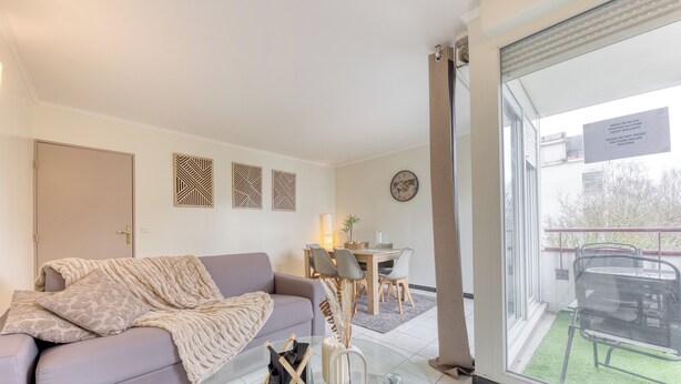 A modern living room with a sofa, a glass coffee table, and a dining area with chairs and a table.