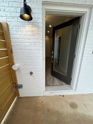 A white brick wall with a wooden door and a black pendant light. - ATL Brand New Town Home  (Atlanta)