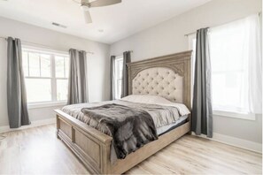 A bedroom with a large bed, wooden headboard, and a ceiling fan.