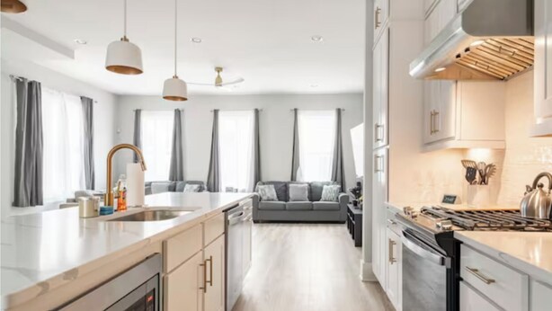 Een moderne keuken met een centraal eiland, een ingebouwde oven en roestvrijstalen apparatuur.