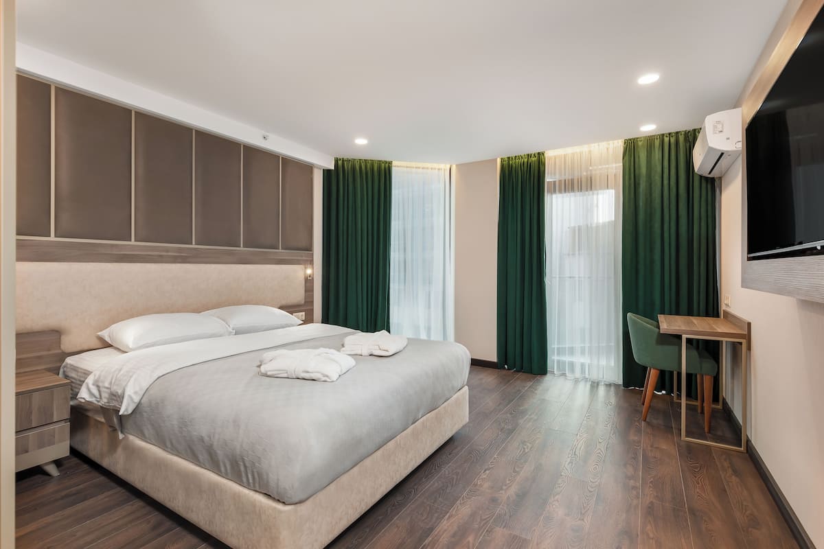 Quarto de hotel moderno com uma cama grande, uma escrivaninha e uma televisão.