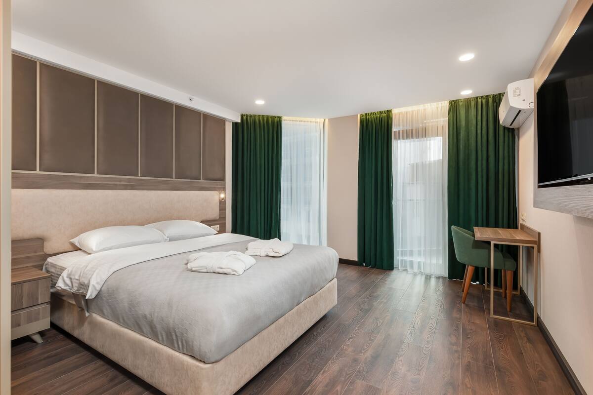 Ein modernes Hotelzimmer mit einem großen Bett, einem Schreibtisch und einem Fernseher.